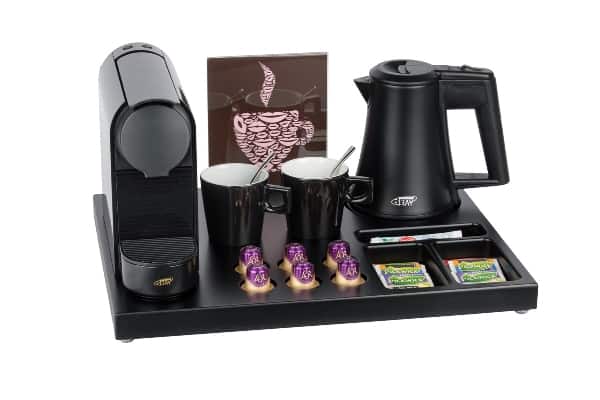 Large hospitality tray made of black brown MDF wood with left a coffee machine and right a black kettle and black coffee cups and a A5 leaflet holder
